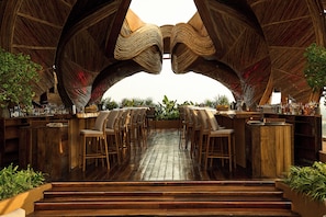 An outdoor bar area with wooden flooring, bar stools, and a unique arched ceiling structure. - InterContinental Bangkok Sukhumvit by IHG (Bangkok)