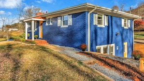 Une maison à deux étages, avec une façade bleue, des boiseries blanches et un porche à l’avant.