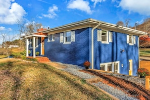 Uma casa de dois andares com fachada azul, detalhes brancos e varanda frontal.