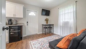 A compact living space with a kitchenette, a dining area, and a seating area with a patterned rug.