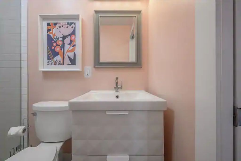 A bathroom with a toilet, sink, and a framed abstract painting on the wall.
