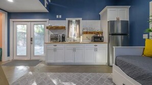 Cocina compacta con armarios blancos, un refrigerador y un microondas.