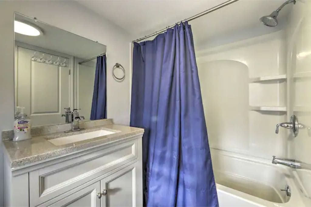 A bathroom with a white sink, mirror, and shower.