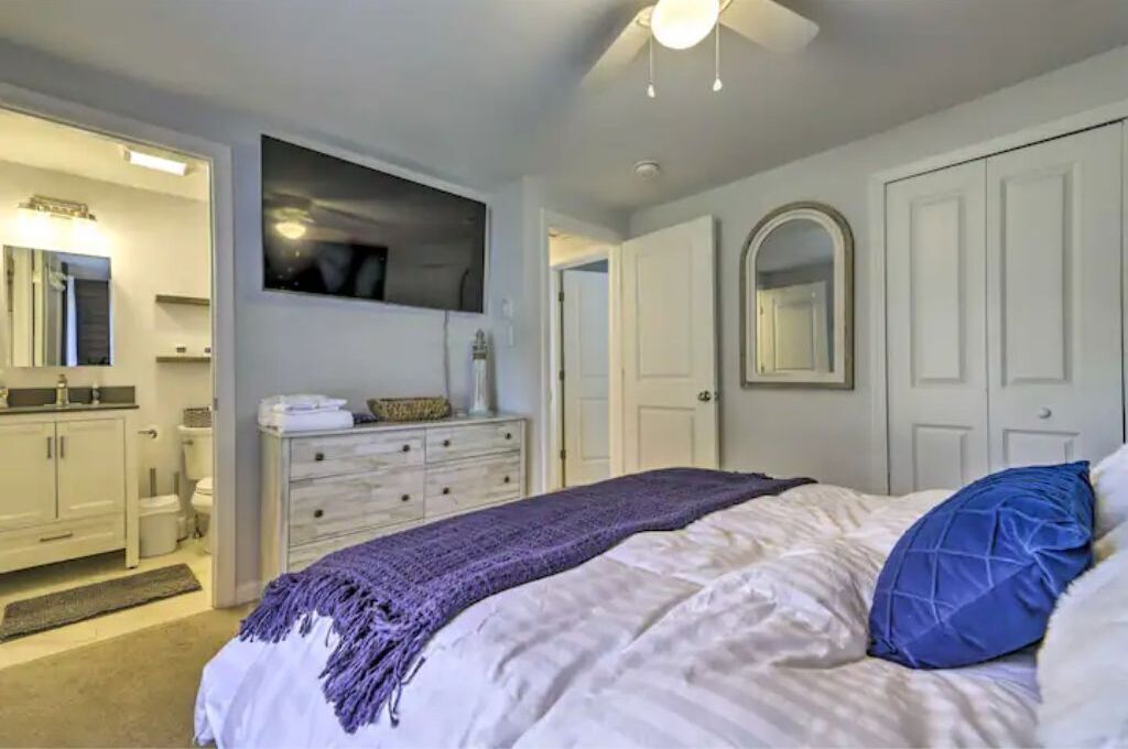 A bedroom with a bed, a dresser, a mirror, and a ceiling fan.