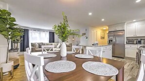 A modern kitchen with white cabinets, a stainless steel refrigerator, and a built-in oven. - NEW! Updated Mystic Home w/ Sauna, Hot Tub & Deck (Groton)