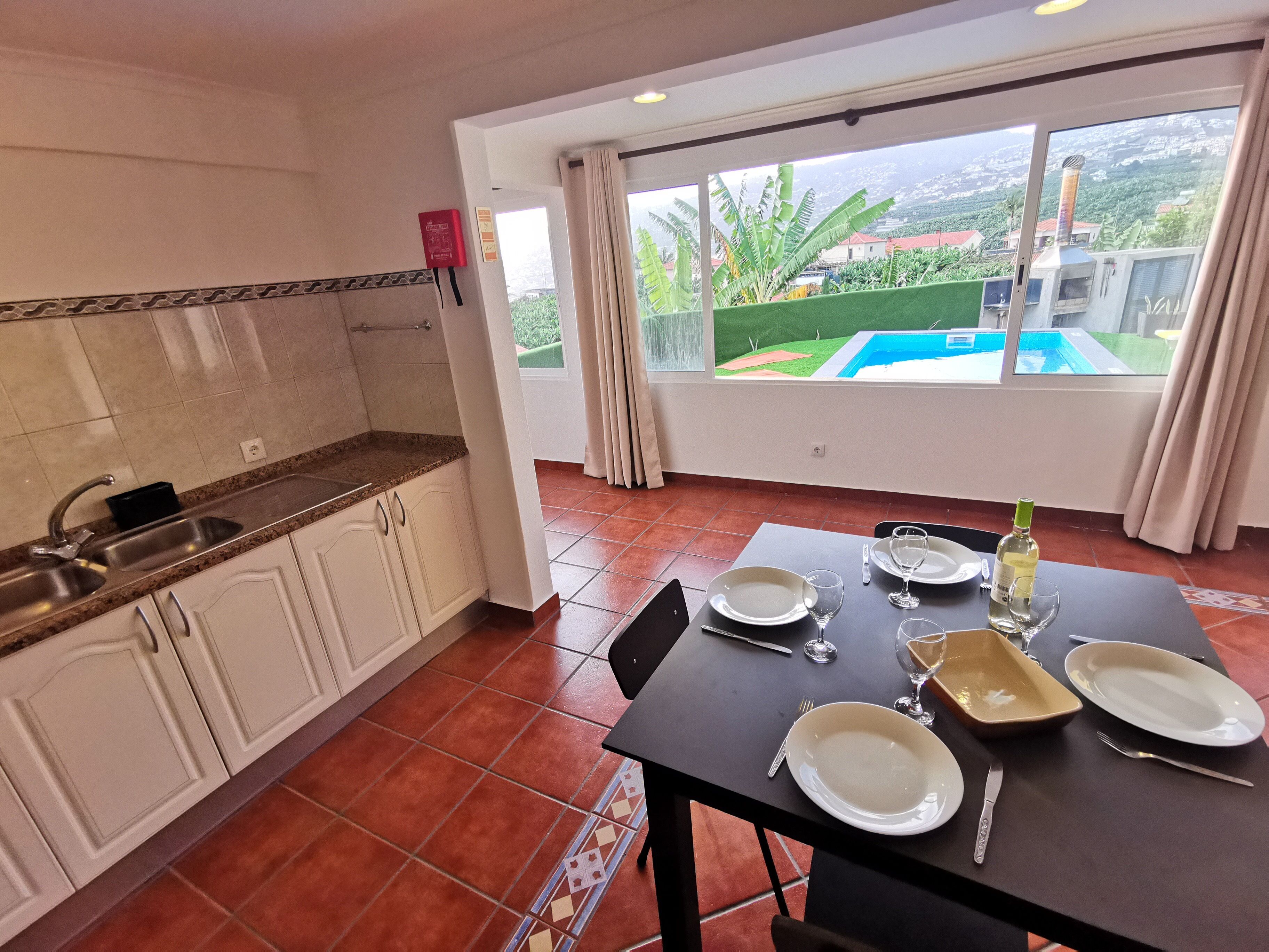A kitchen with a sink, cabinets, and a dining area with a table set for two.