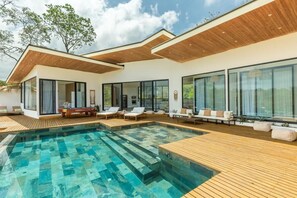 A modern house with a pool, wooden deck, and large windows.