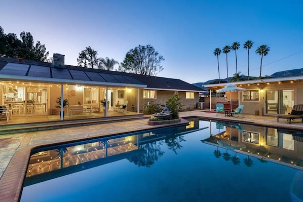 Ein modernes Haus mit Swimmingpool, Solaranlage und Außenbereich mit Sitzgelegenheit.