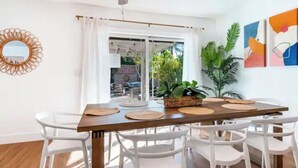 A dining area with a wooden table, white chairs, and a ceiling fan. - Luxury Tropical Modern Pool Estate/NO PARTIES (San Bernardino)