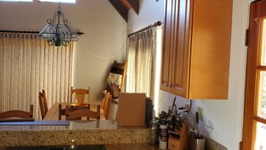 A kitchen with wooden cabinets, a granite countertop, a stainless steel stove, and a chandelier. - Serenity View, Peaceful & Cheerful 3BD Cabin. (Groveland)
