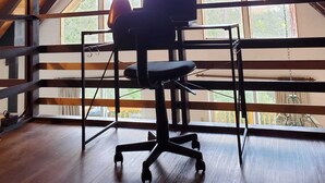 A high-ceilinged attic room with a wooden floor, a desk with a computer, and a chair. - Serenity View, Peaceful & Cheerful 3BD Cabin. (Groveland)