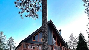 A two-story log cabin with a balcony and a staircase leading to the entrance. - Serenity View, Peaceful & Cheerful 3BD Cabin. (Groveland)