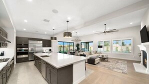 Una cocina moderna con una isla grande, electrodomésticos integrados y un comedor con vistas.