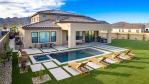 Una casa moderna con piscina, mobiliario de exterior y vistas a las montañas.