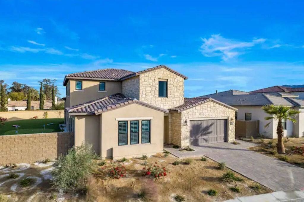 A two-story house with a stone facade, a garage, and a well-maintained lawn.