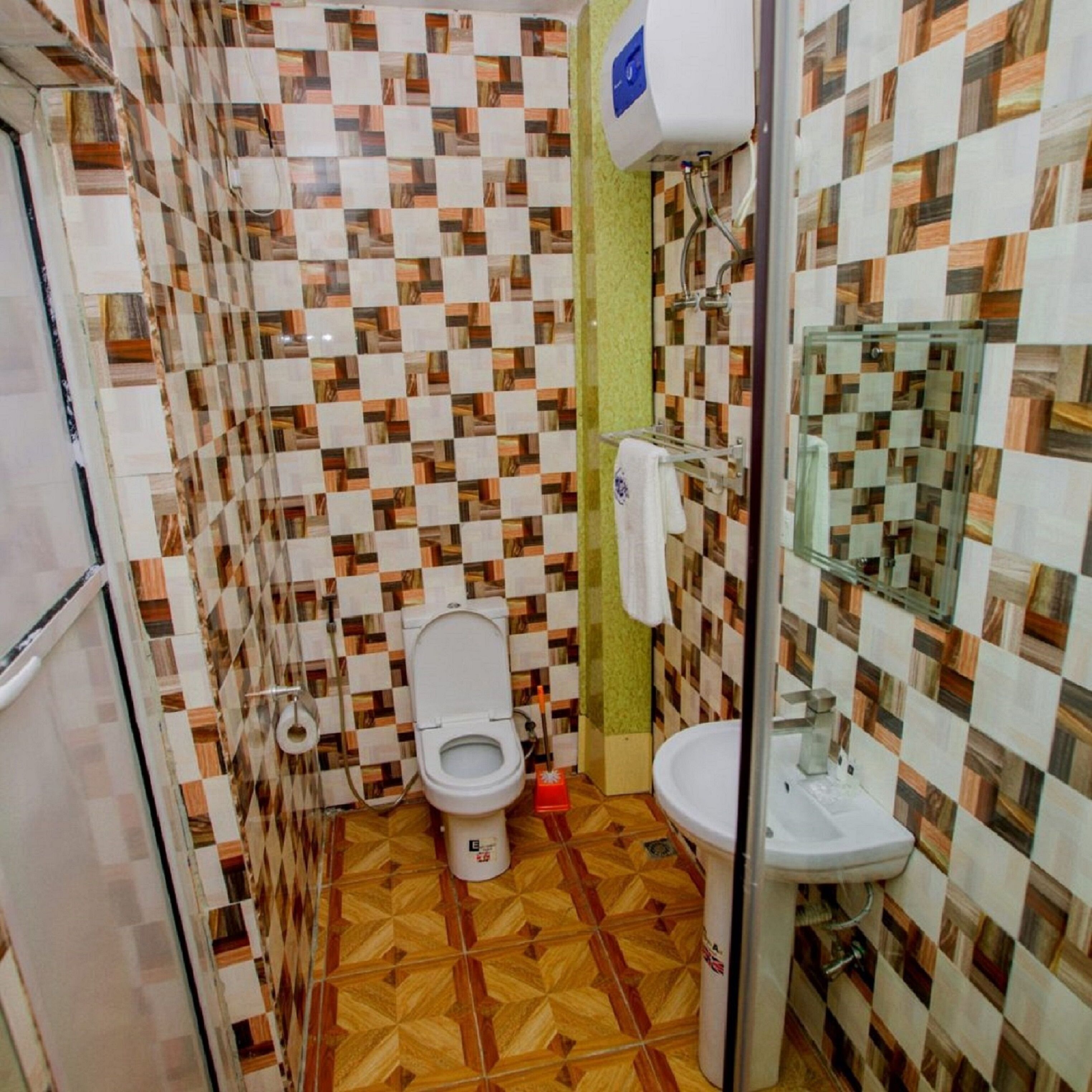 A bathroom with a checkered tile pattern, a toilet, a sink, and a glass shower enclosure.