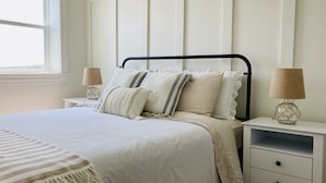A neatly arranged bedroom with a bed, two bedside tables, and a window.