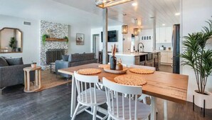 Ein modernes Wohnzimmer mit einem Holzesstisch, weißen Stühlen und einem Kamin.