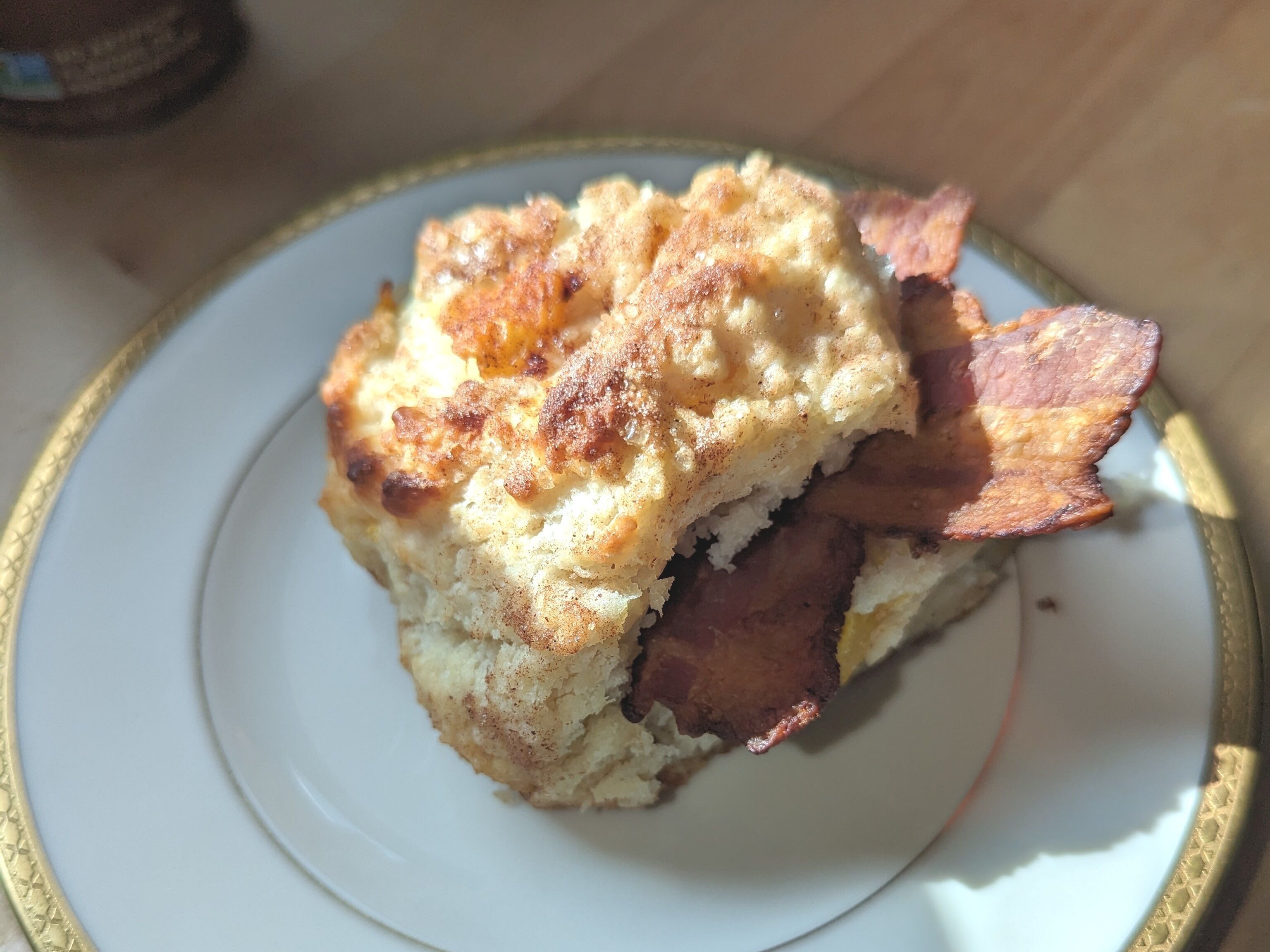 A plate with a biscuit and bacon.