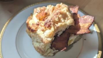 A plate with a biscuit and bacon.