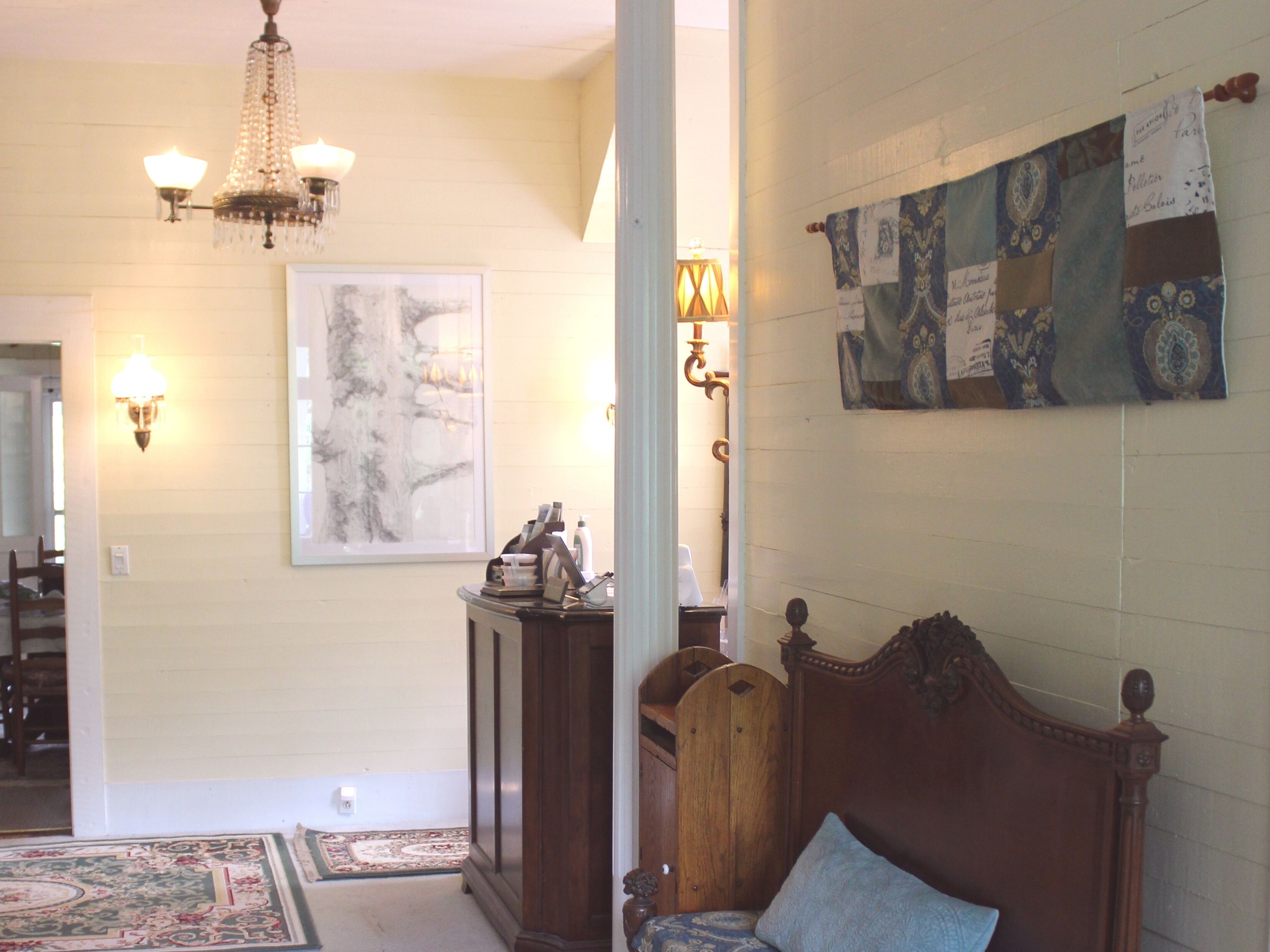 Quarto com cama, um lustre, luminária na parede, uma obra de arte emoldurada e tapeçaria decorativa.