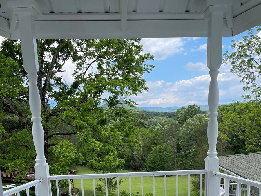 A covered outdoor area with a white railing, two ornate white chairs, and a small white table.