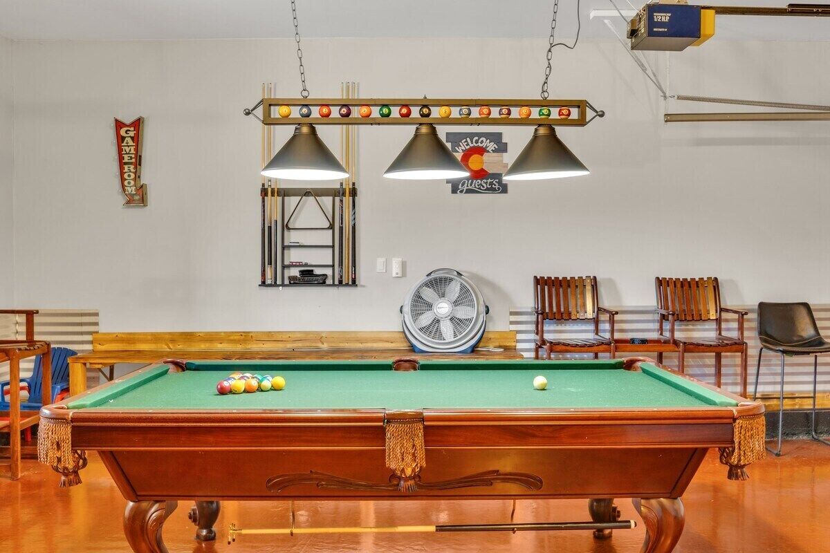 A pool table with balls, a fan, and a 'Welcome Guests' sign.