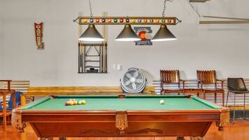 A pool table with balls, a fan, and a 'Welcome Guests' sign.