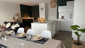 A modern living room with a dining area, a kitchen, and a staircase. - Sea view in the heart of Contis plage (Saint-Julien-en-Born)
