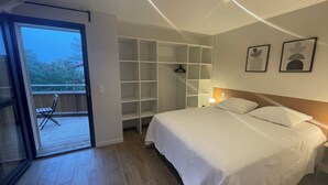A bedroom with a bed, a wardrobe, a balcony, and a door leading outside. - Sea view in the heart of Contis plage (Saint-Julien-en-Born)