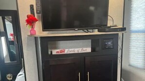 Un espace de vie doté d’un téléviseur à écran plat fixé sur une étagère au-dessus d’une cheminée.