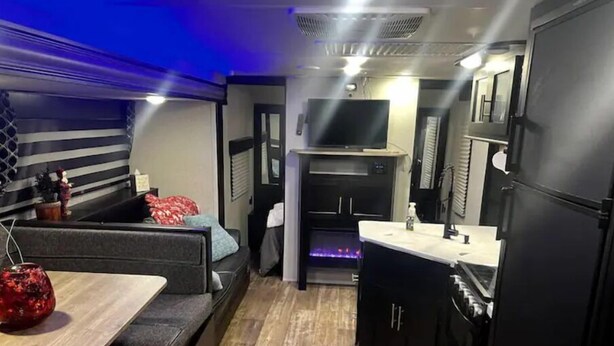 Une cuisine compacte comprenant un coin repas, un four encastré et un petit espace détente avec un canapé et une table.