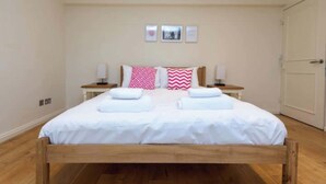 A double bed with white linens, two bedside tables with lamps, and a wooden floor. - Brilliantly located 3BD Home Nr Paddington Station (London)