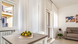 A modern living room with a dining area. There is a table with a bowl of lemons and a potted plant. A sofa and a small side table with a lamp are visible. - Harmony House (Piano di Sorrento)