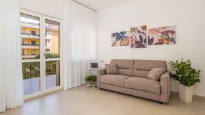 A modern living room with a beige sofa, a small side table, a laptop, and a potted plant. - Harmony House (Piano di Sorrento)