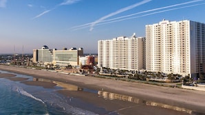 Un hotel frente a la playa con varios edificios altos, un muelle y una playa de arena.