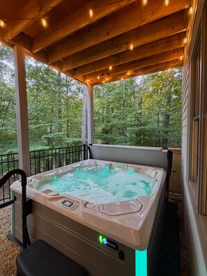 Un bain à remous sous une pergola en bois, avec vue sur une forêt.