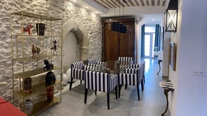 A dining area with striped chairs and a glass table, stone walls, and a wooden ceiling. - LA RENAUDIERE, HYPER CENTER (L'Isle-sur-la-Sorgue)