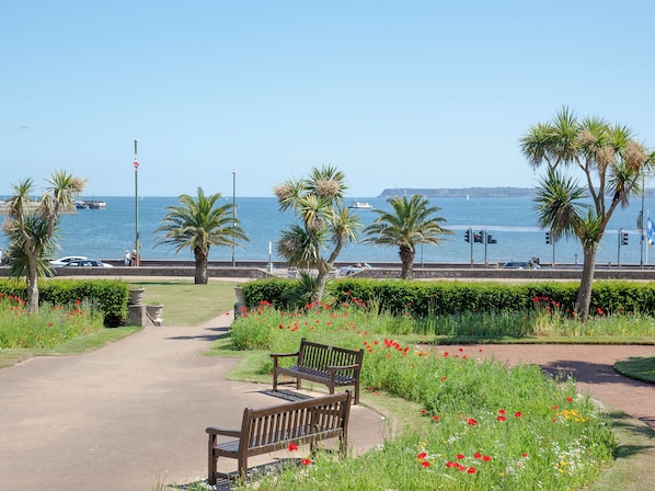 A bench in a park with a view of the sea and boats.