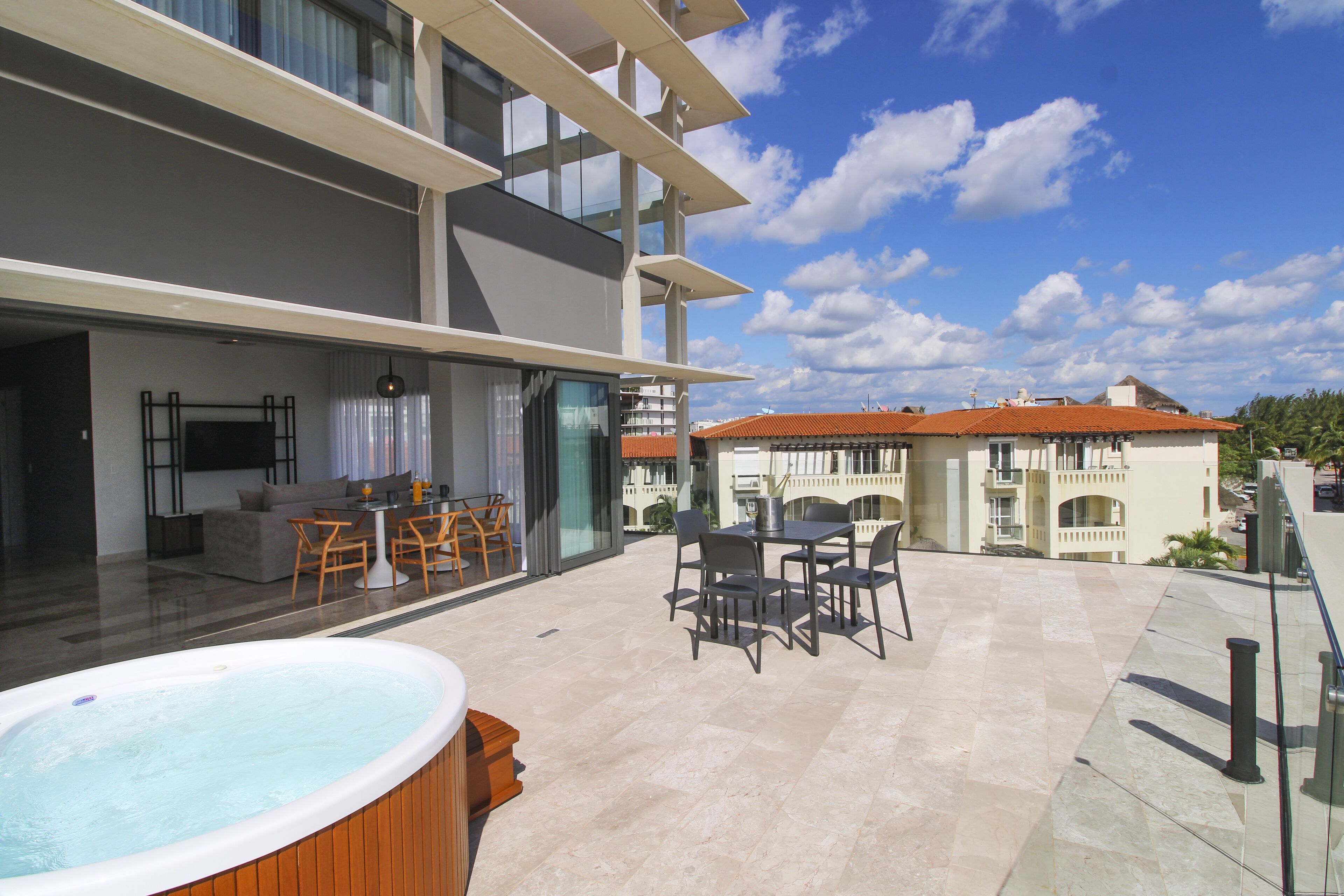 Eine moderne Außenpatio mit Whirlpool, Sitzbereich und Blick auf ein Gebäude mit rotem Ziegeldach.