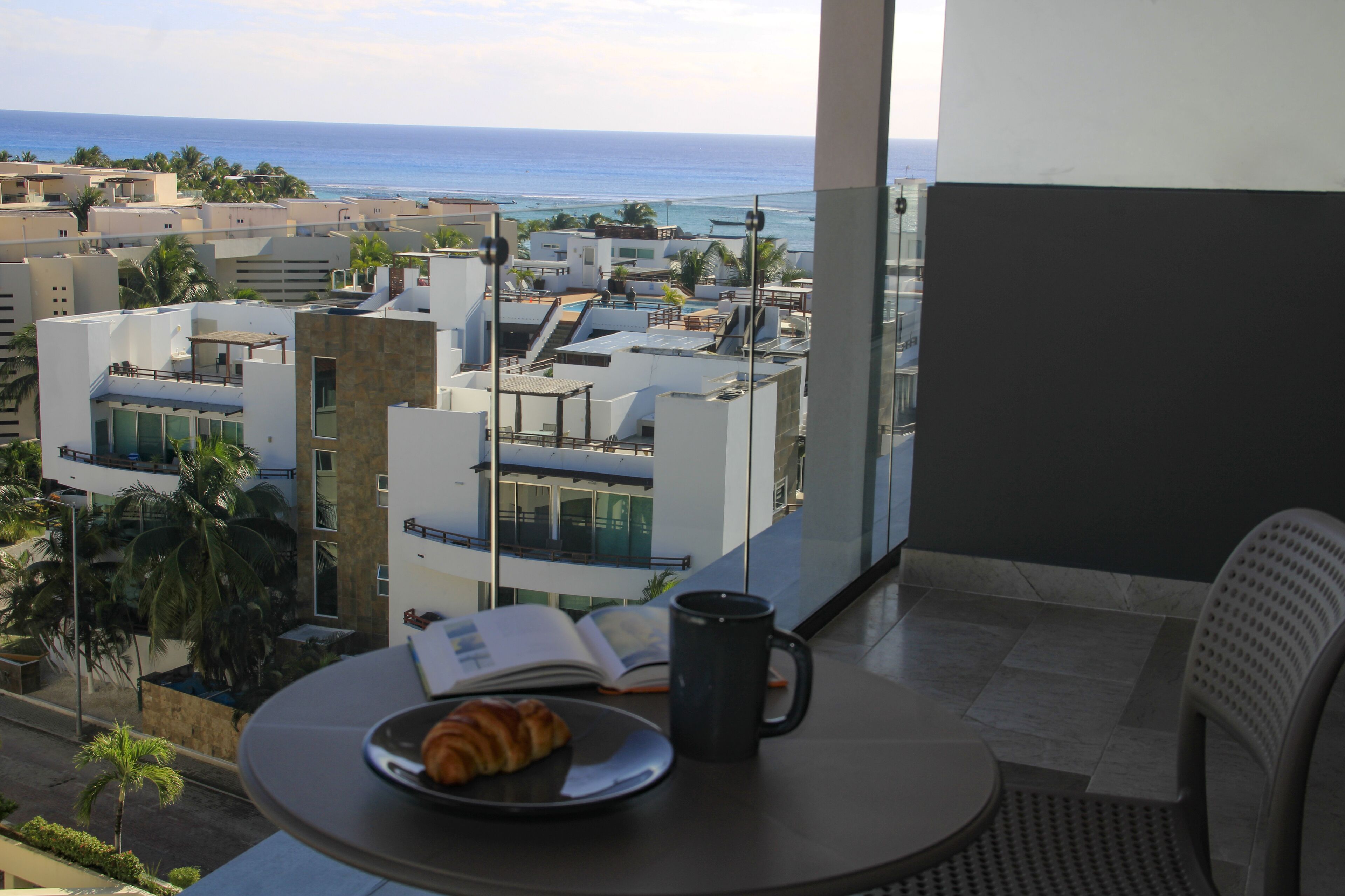 A balcony with a table, a croissant, and a book.