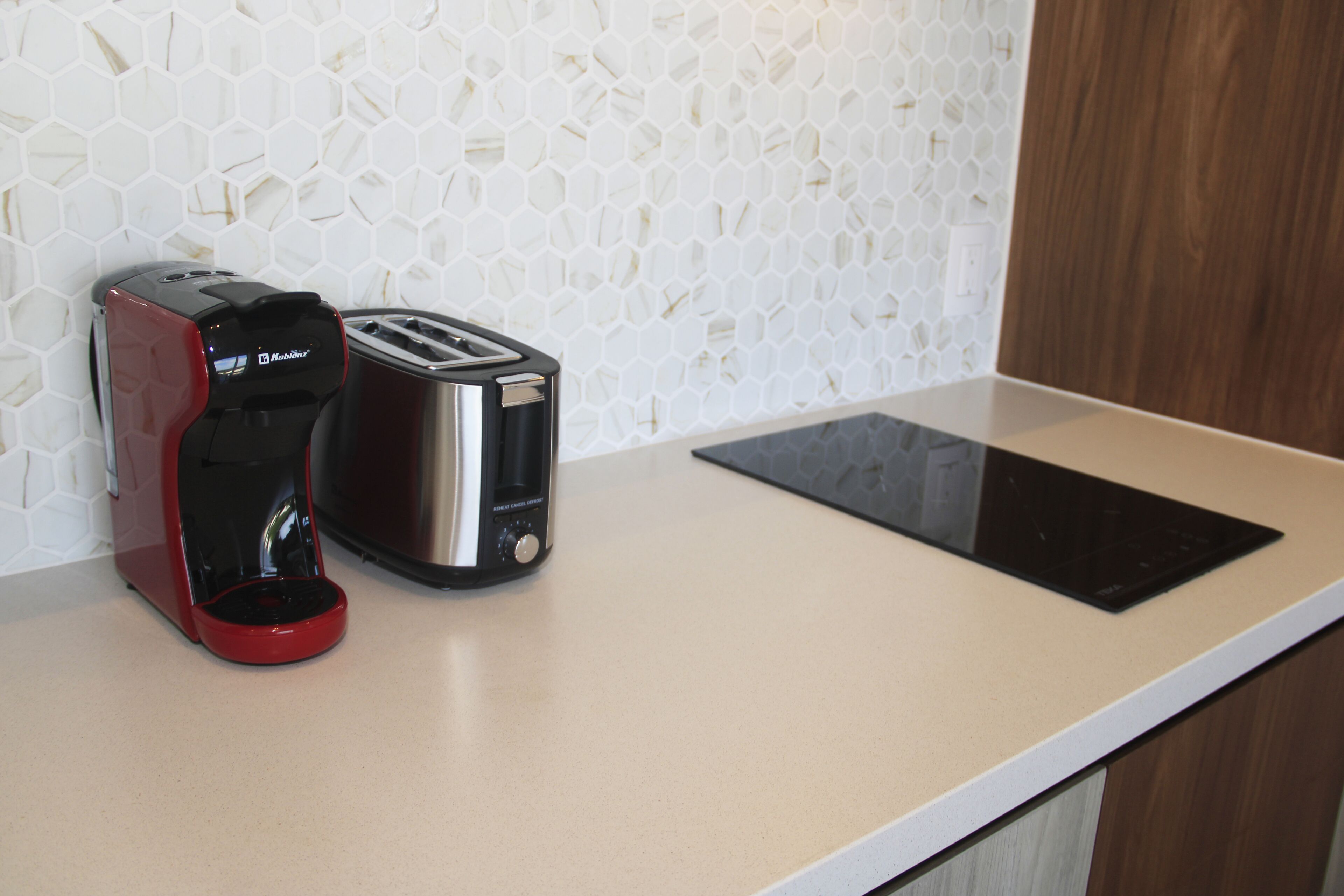 A kitchen counter with a coffee maker, toaster, and induction cooktop.