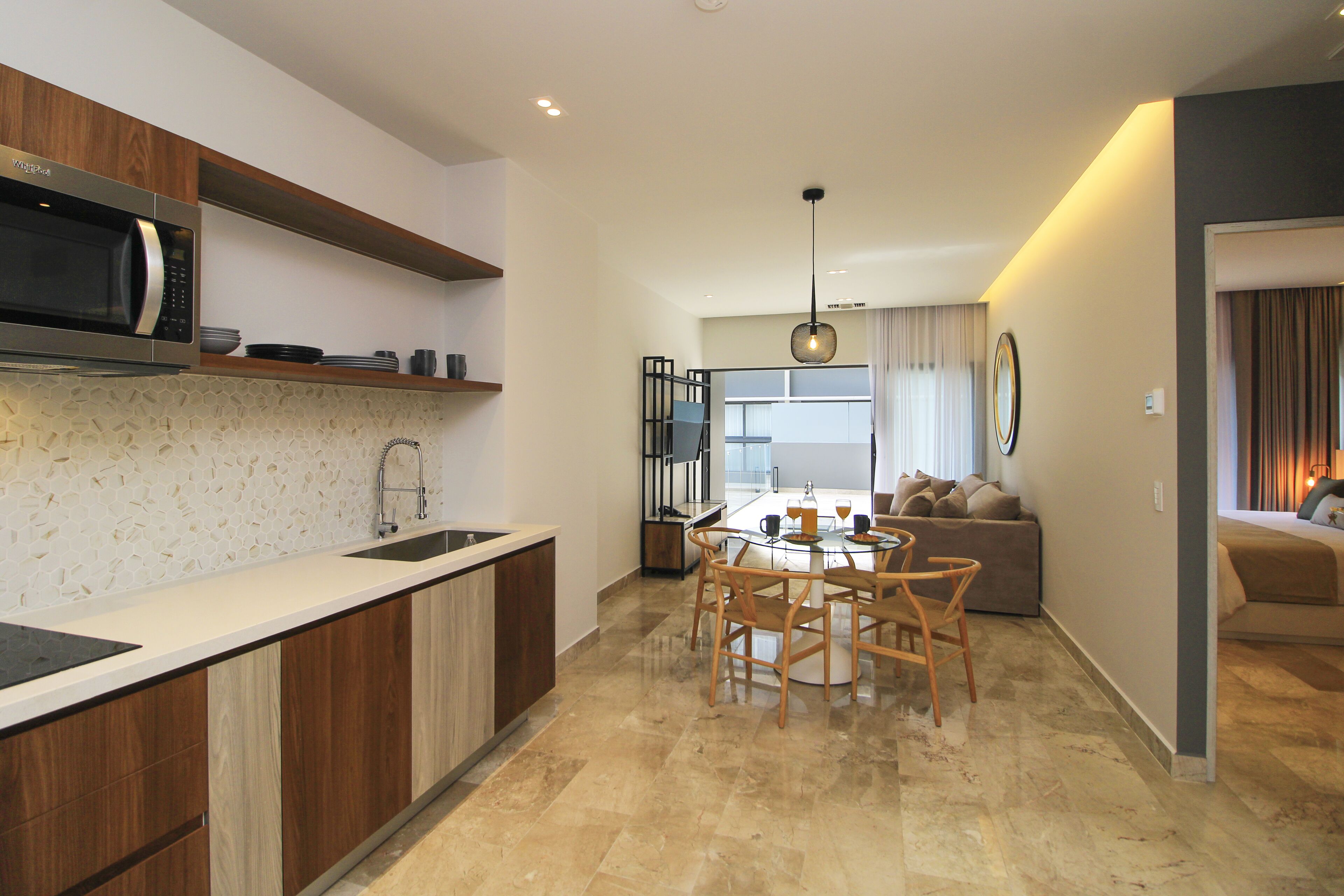 A modern kitchen with a built-in microwave, wooden cabinets, and a glass dining table with chairs.