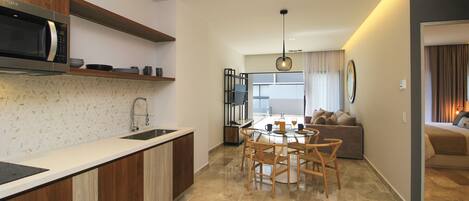 A modern kitchen with a built-in microwave, wooden cabinets, and a glass dining table with chairs.