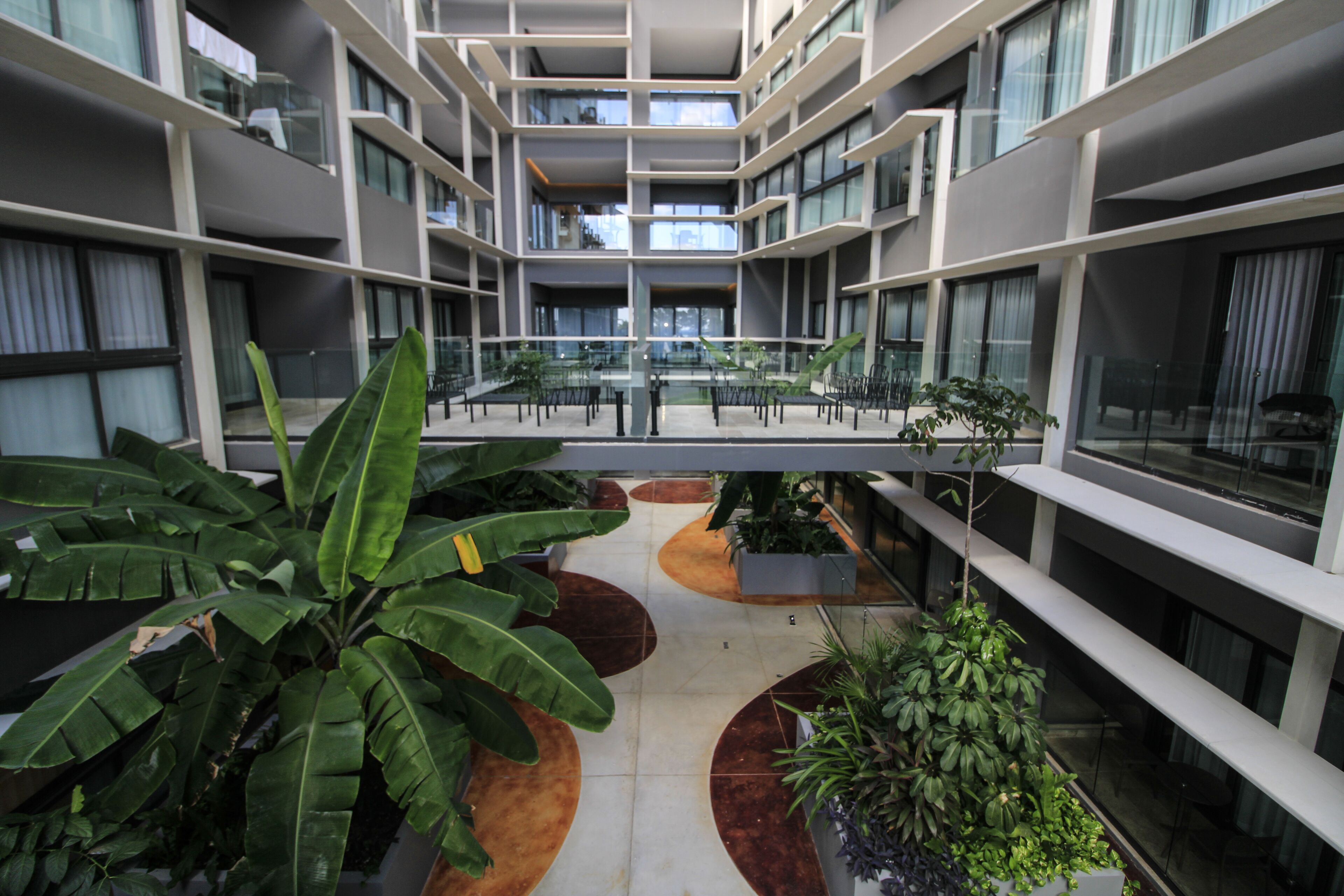 Un atrium moderne à plusieurs étages, doté de rampes en verre et agrémenté de plantes d’intérieur.