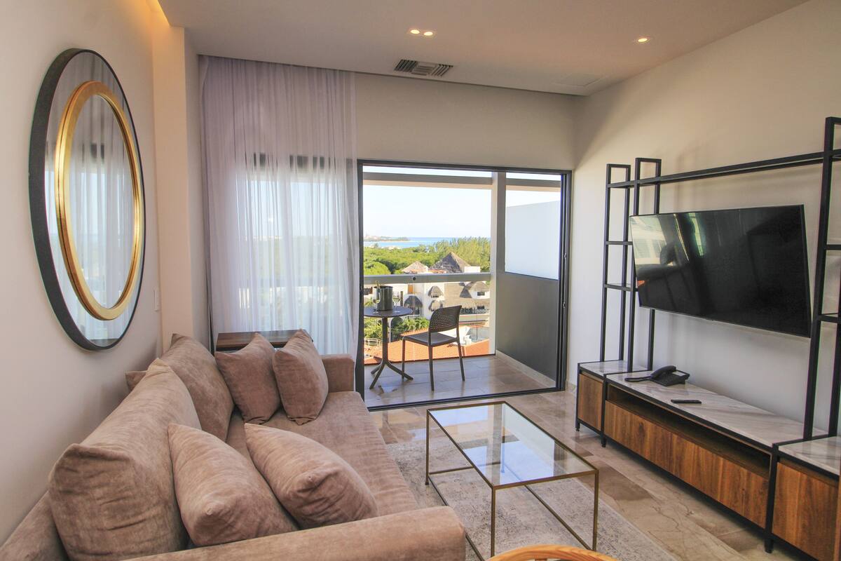 A modern living room with a sofa, a glass coffee table, and a flat-screen TV.