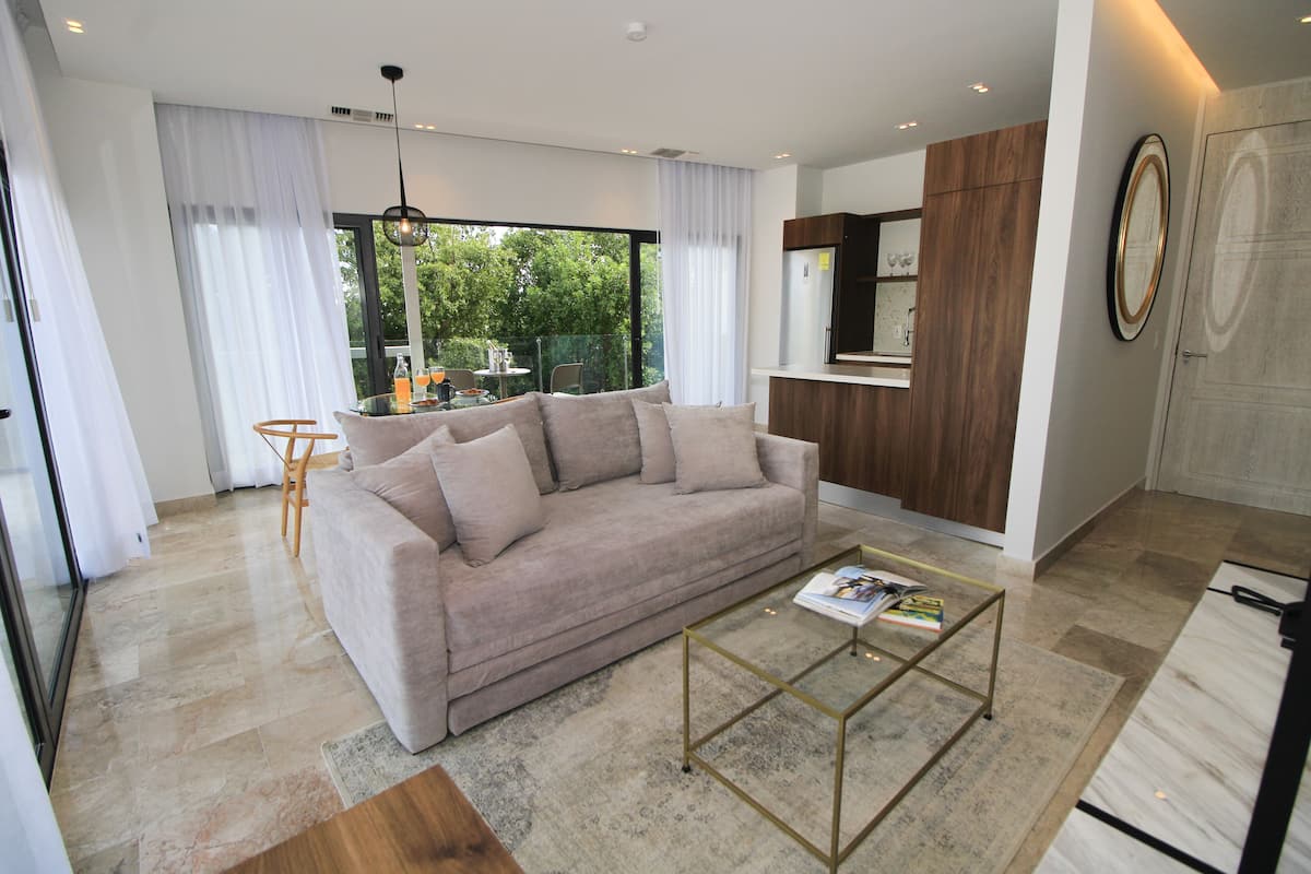 A modern living room with a sofa, coffee table, and a dining area with chairs.