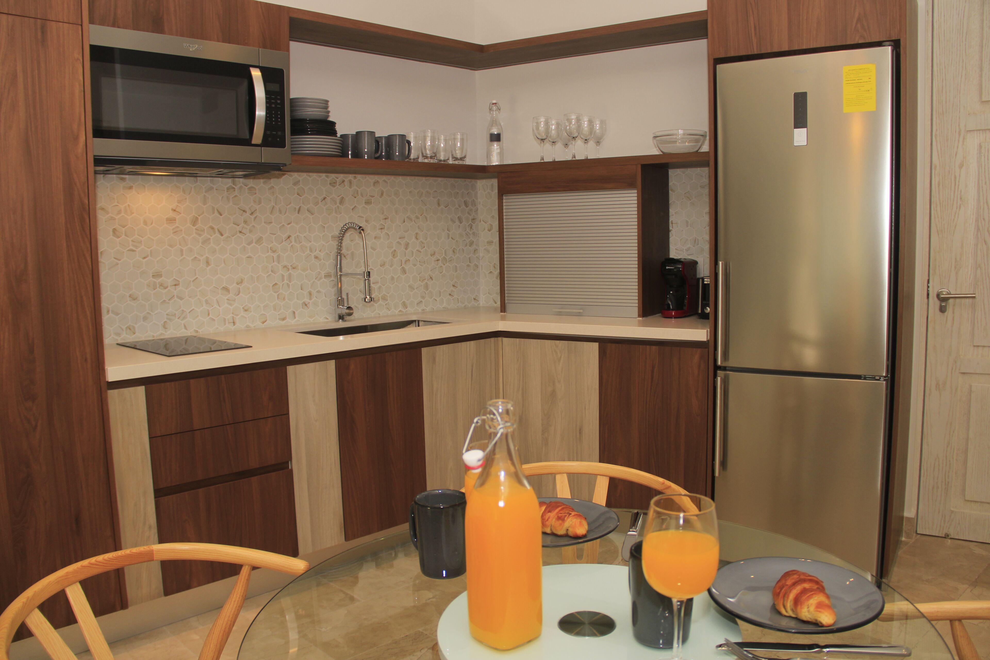 Cozinha compacta com micro-ondas, geladeira e área de refeições com mesa posta para o café da manhã.