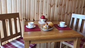 A wooden table with a bowl of apples, a plate of pastries, and two cups on red placemats. - Tiny House Glamping - On the Wild Atlantic Way 5 minutes from Tralee (Tralee)
