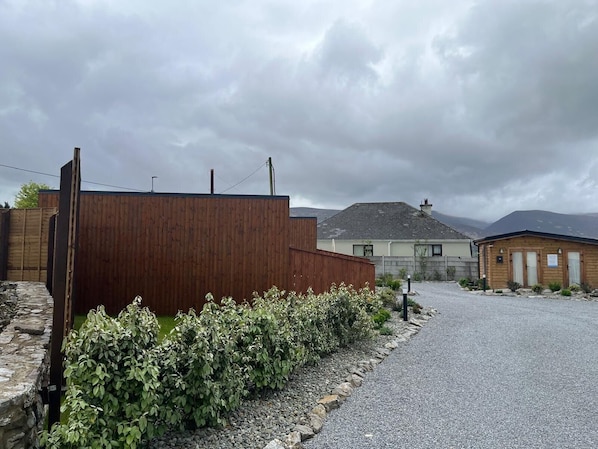 A rural setting with a wooden building, a gravel driveway, and a stone wall. - Tiny House Glamping - On the Wild Atlantic Way 5 minutes from Tralee (Tralee)